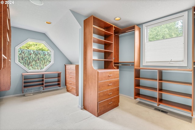 walk in closet featuring light carpet and lofted ceiling