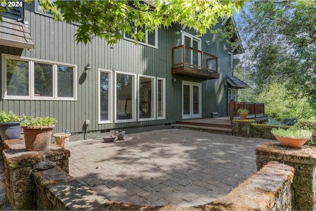 back of property featuring a balcony, french doors, a patio area, and a jacuzzi