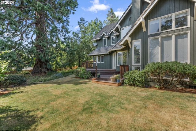 back of property featuring a deck and a lawn