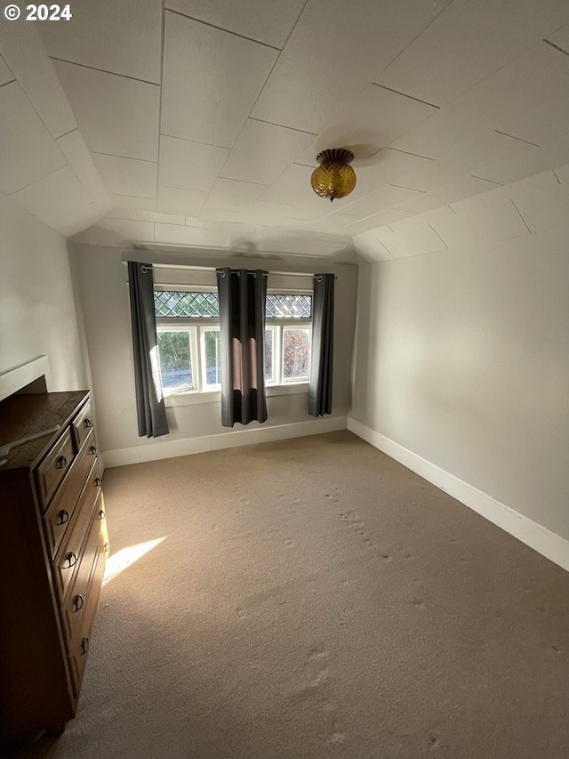 carpeted empty room with vaulted ceiling