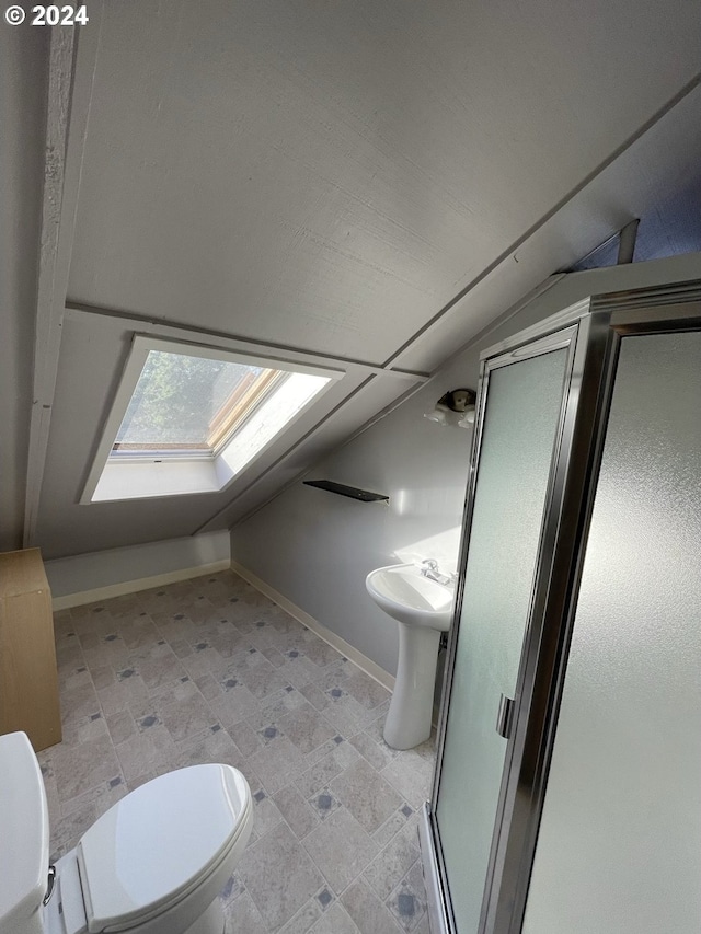 bathroom with sink, toilet, a shower with shower door, and vaulted ceiling with skylight