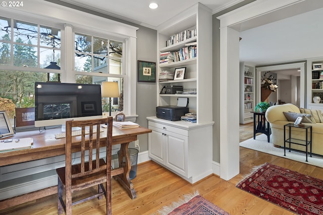 office space with light hardwood / wood-style floors, ornamental molding, and built in shelves