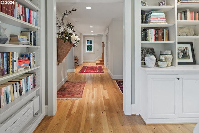 corridor with built in features and light hardwood / wood-style floors