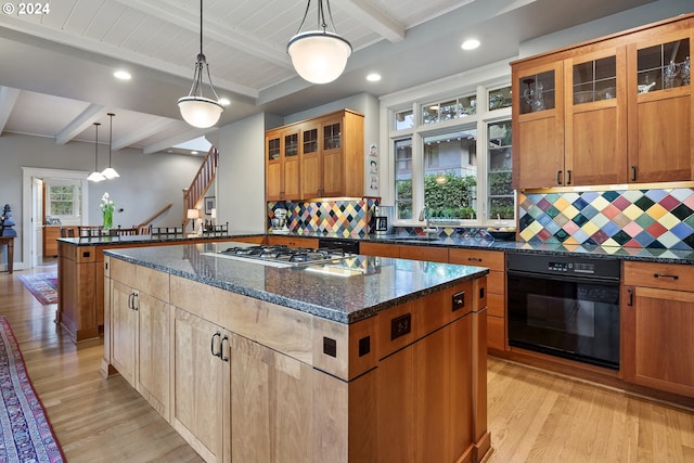 kitchen featuring black oven, decorative light fixtures, a kitchen island, beam ceiling, and stainless steel gas stovetop