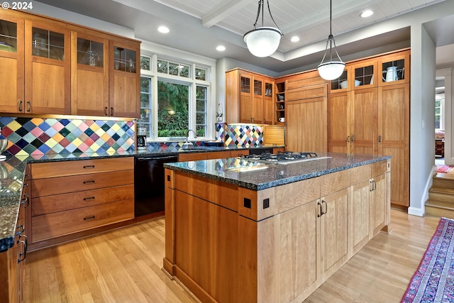 kitchen with dark stone countertops, stainless steel gas cooktop, beamed ceiling, a kitchen island, and black dishwasher