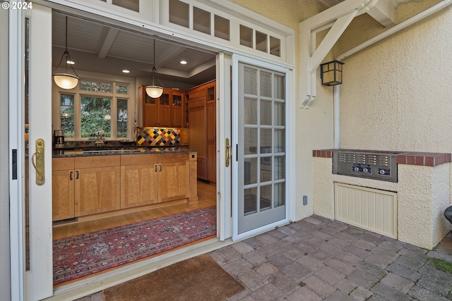 exterior space with beam ceiling, decorative light fixtures, backsplash, and sink