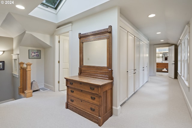 hall with light colored carpet and lofted ceiling with skylight