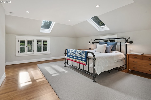 bedroom featuring lofted ceiling with skylight and hardwood / wood-style floors