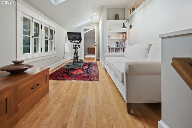 living room featuring light hardwood / wood-style flooring and vaulted ceiling with skylight