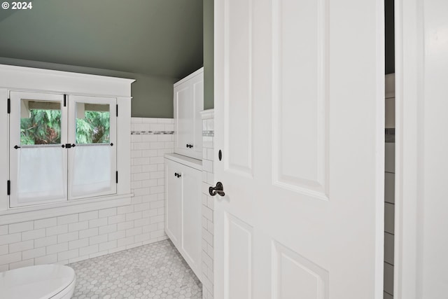 bathroom with tile walls, toilet, and tile patterned floors