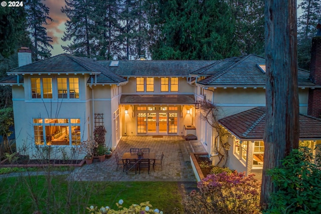 back house at dusk with a patio area and french doors