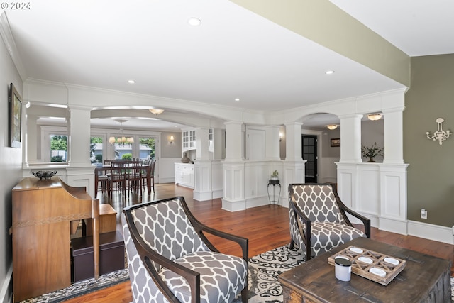 living room with ornate columns, wood-type flooring, and ornamental molding