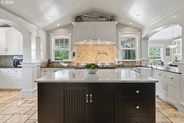 kitchen featuring decorative backsplash, white cabinets, a center island, and vaulted ceiling