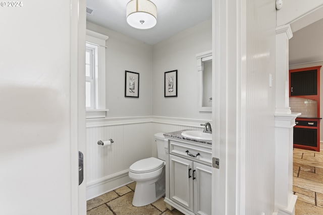 bathroom with vanity, toilet, backsplash, and ornate columns