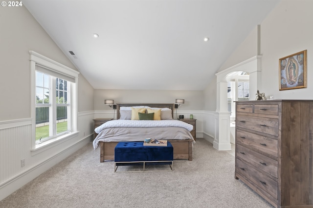 bedroom with lofted ceiling, light colored carpet, and ornate columns