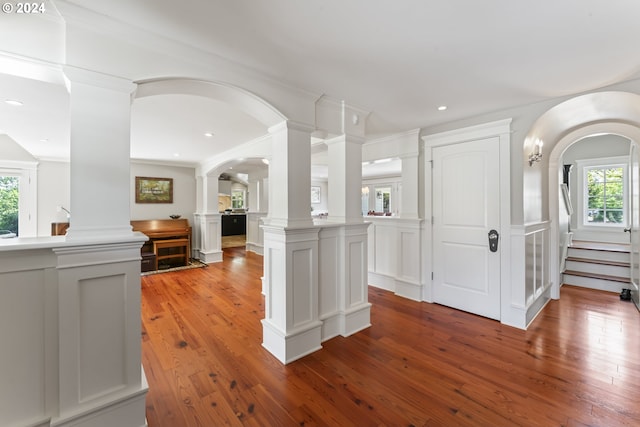 kitchen featuring crown molding, wood-type flooring, a kitchen island, and decorative columns