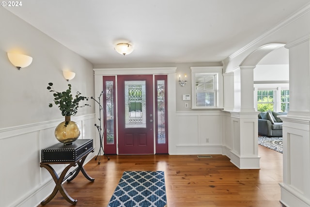 foyer entrance featuring ornamental molding, hardwood / wood-style flooring, and decorative columns