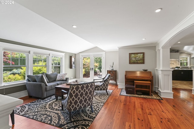 living room with french doors, ornate columns, ornamental molding, vaulted ceiling, and light hardwood / wood-style floors