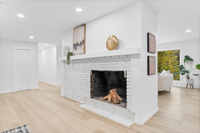 living room featuring a brick fireplace and light wood-type flooring