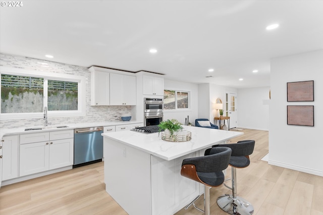 kitchen featuring sink, stainless steel appliances, a center island, and white cabinets