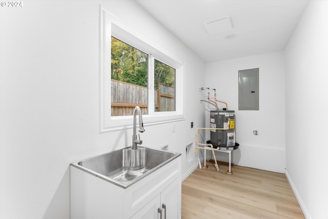 laundry room with sink, electric panel, cabinets, electric water heater, and light hardwood / wood-style floors