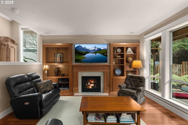 sitting room with visible vents, a lit fireplace, light wood finished floors, and a wealth of natural light