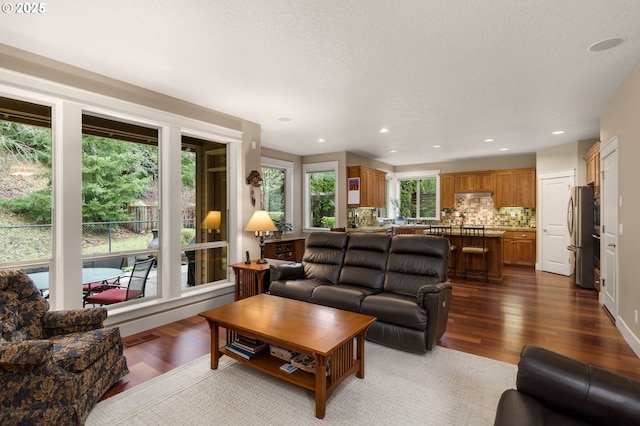 living area featuring recessed lighting, dark wood-style flooring, visible vents, and a textured ceiling