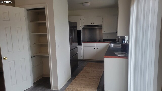 empty room with dark wood-type flooring, a textured ceiling, a baseboard radiator, and a wood stove