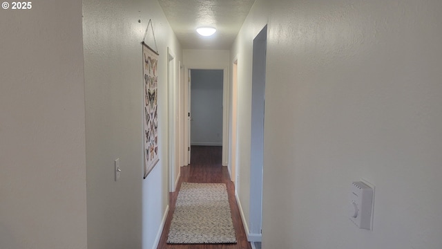 corridor featuring a textured ceiling and baseboards