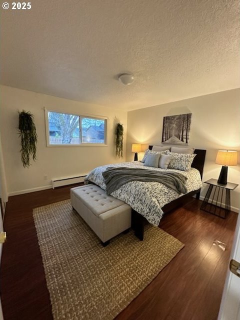 bedroom featuring a textured ceiling, baseboard heating, wood finished floors, and baseboards