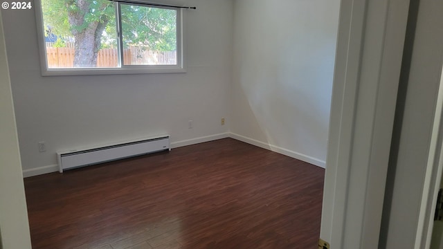 empty room featuring a baseboard heating unit, dark wood-type flooring, and baseboards