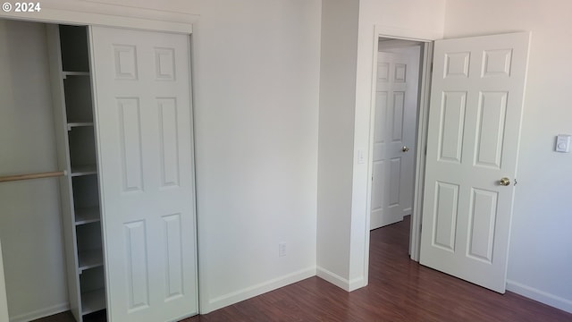 unfurnished bedroom with baseboards and dark wood-type flooring