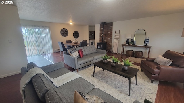 living area with baseboard heating, a wood stove, a textured ceiling, and baseboards