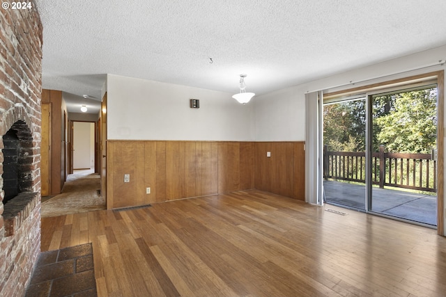 empty room featuring a brick fireplace, a textured ceiling, and hardwood / wood-style floors