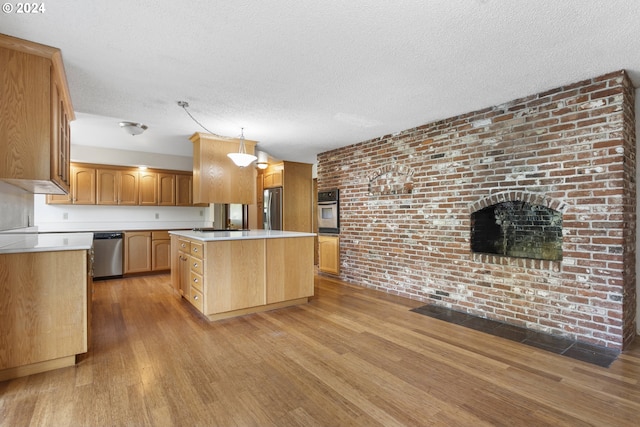 kitchen featuring pendant lighting, light hardwood / wood-style flooring, appliances with stainless steel finishes, a center island, and a textured ceiling