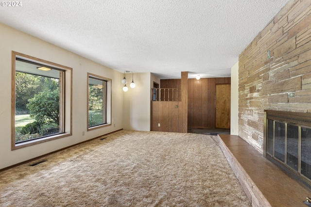 unfurnished living room featuring dark carpet, a textured ceiling, and a fireplace