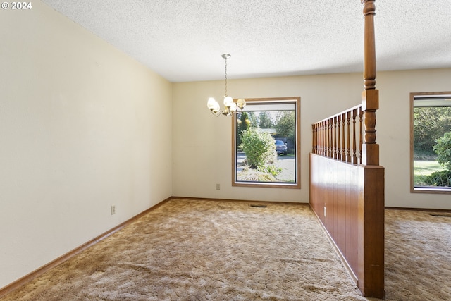 unfurnished dining area with a textured ceiling, carpet flooring, and a healthy amount of sunlight