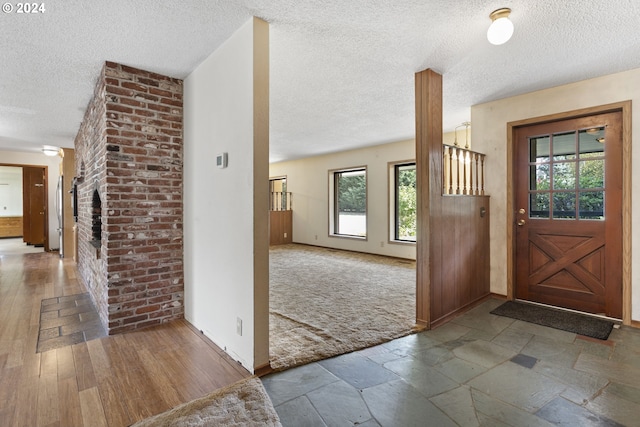 carpeted entrance foyer featuring a textured ceiling, a fireplace, and baseboards