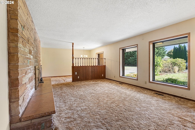 unfurnished living room with light carpet, an inviting chandelier, and a textured ceiling