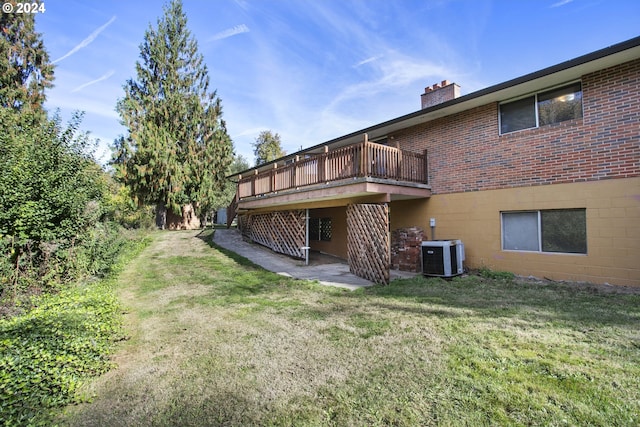 back of house with a yard, brick siding, central AC unit, and a chimney