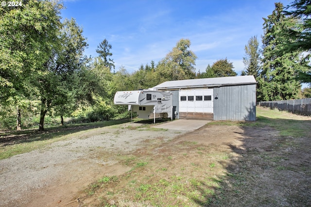 view of front of home with an outbuilding, driveway, fence, and a detached garage