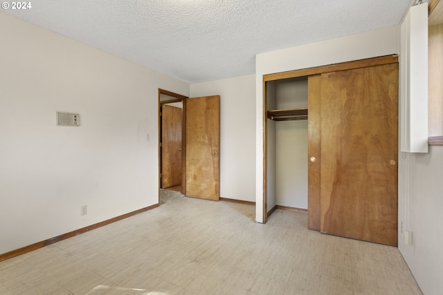 unfurnished bedroom with a textured ceiling, a closet, baseboards, and light floors