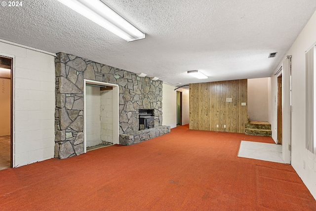 basement featuring carpet flooring, wooden walls, and a textured ceiling