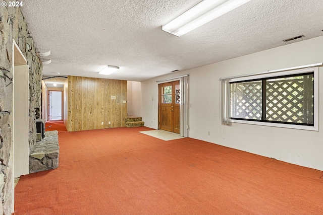 below grade area featuring visible vents, wood walls, carpet flooring, and a textured ceiling