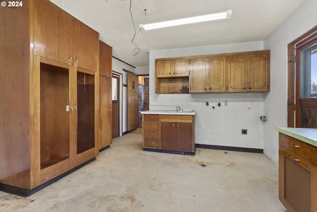 kitchen featuring light carpet, sink, and a textured ceiling