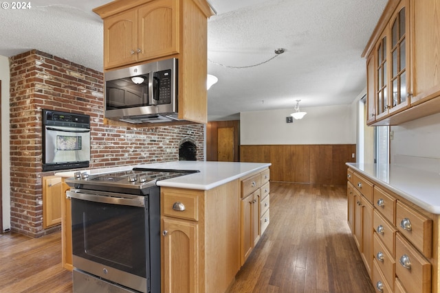 kitchen featuring wood walls, a kitchen island, a textured ceiling, stainless steel appliances, and hardwood / wood-style floors