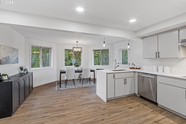 kitchen with hanging light fixtures, kitchen peninsula, light hardwood / wood-style flooring, and stainless steel dishwasher