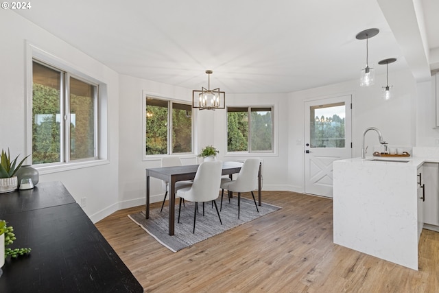 dining room with a notable chandelier, light wood-type flooring, and sink