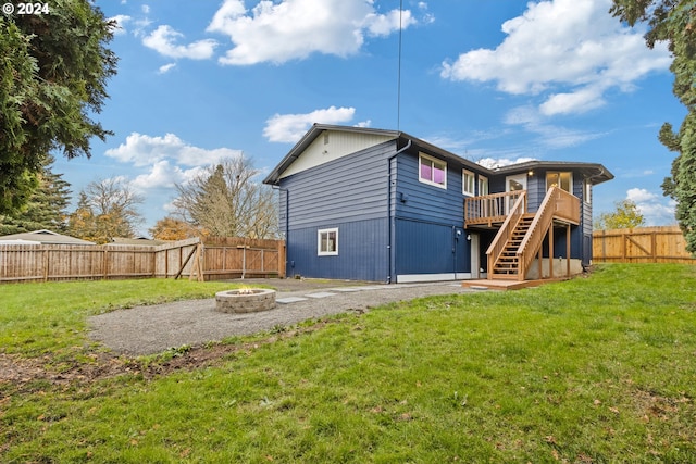 back of house with a lawn, a fire pit, and a deck