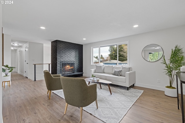 living room with a brick fireplace and light wood-type flooring